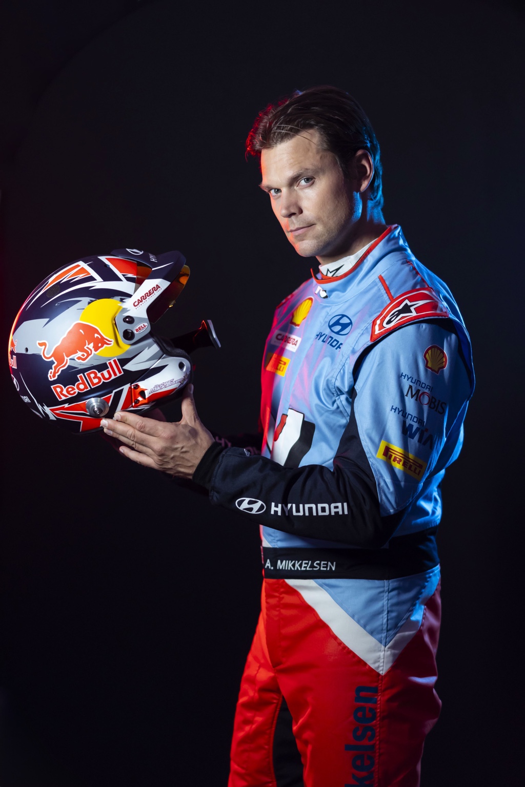 Andreas Mikkelsen holding his helmet in Hyundai Motorsport racewear